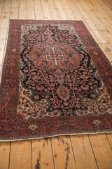 Perspective view of an antique Farahan Sarouk rug's navy field and sprawling tree of life design.