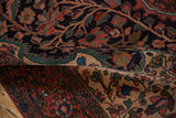 Folded antique Farahan Sarouk rug showing the dense floral ornamentation on its hand-knotted pile.