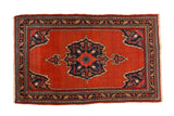 Vintage Bijar rug with a navy blue center medallion and spandrels on an open brick red field.
