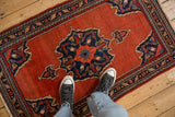 Overhead view of a vintage Bijar rug showing its scale and central navy medallion on a brick red field.