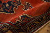A vintage Bijar rug folded to show the dense brick red pile and detailed floral border.
