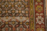 Kurdish runner's charcoal field with blossom motifs, madder red and green gold bordered.