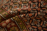 Folded vintage Kurdish runner showcasing hand-knotted pile, rose, charcoal, green gold floral motifs.