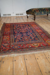 Perspective view of an antique Kurdish Hamadan rug with a navy Herati field and wide red border.