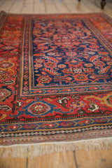 A low perspective across the antique Kurdish rug's intricate navy field and red border.