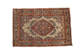 Antique Persian Tabriz mat with a scalloped shield medallion in rust and blue on an ivory field.