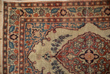Corner detail of an antique Tabriz rug showing the stylized book cover spandrel and floral border.