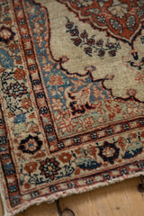 Corner detail of an antique Tabriz rug showing the stylized spandrel and the main border's leaf motifs.