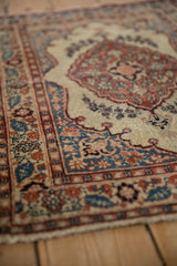 Angled view of an antique Tabriz rug showing the textured pile and traditional spandrel details.