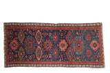 Antique Soumac rug runner with large-scale gul medallions in rich gem tones on a deep navy blue field.