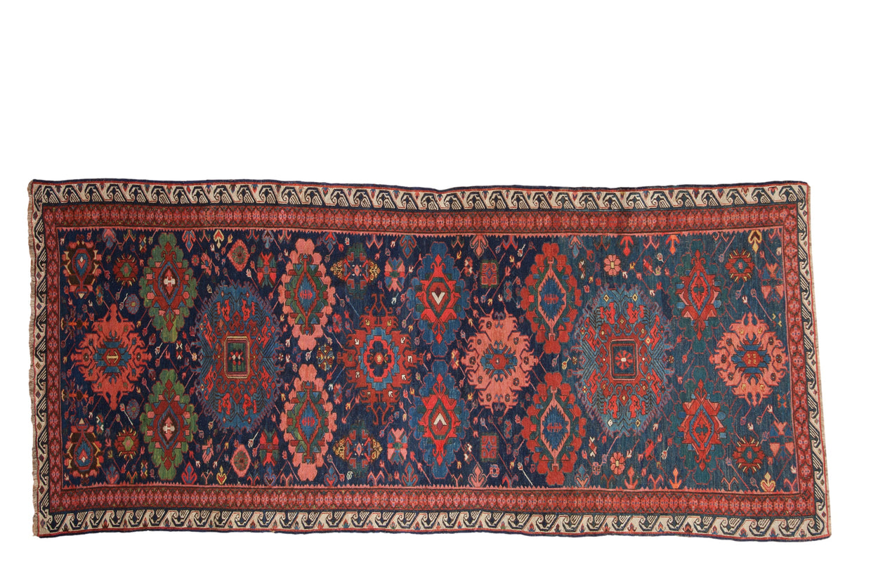Antique Soumac rug runner with large-scale gul medallions in rich gem tones on a deep navy blue field.