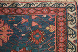 Corner of an antique Caucasus rug showing the reciprocating wave and geometric red borders.