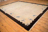Chinese Art Deco carpet corner: bold black border frames ivory field with blue motifs.