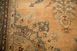 A stylized bird on a Tree of Life branch on a distressed, sand-colored antique Persian Yezd carpet.