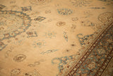 Angled view across the sandy field and detailed floral border of an antique Yezd carpet.