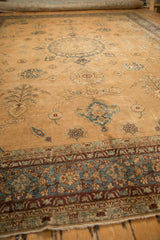 Low angle perspective of a distressed antique Yezd carpet, showcasing the intricate border and sand-colored field.