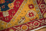 Close-up on the antique Anatolian rug's pile showing geometric running-T details in saffron yellow.