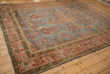 Angled view of a distressed Mahal carpet's pink floral border and abrashed blue field.
