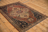 Vintage Farahan Sarouk rug from an angle, highlighting the red and navy floral medallion design.