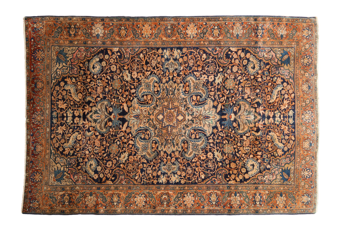 Vintage Farahan Sarouk rug with a central medallion and scrolling florals in copper and sand on a navy blue ground.