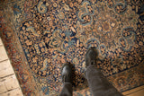 Low-pile texture of a vintage Farahan Sarouk highlights its intricate scrolling vine pattern in bronze and navy.
