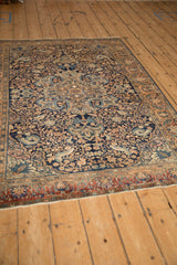 Angled perspective view of a vintage Persian rug highlighting the intricate scrolling vines and central medallion.