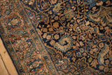 Intricate scrolling vine pattern in navy and bronze showing the mostly even wear of a vintage Farahan Sarouk rug.