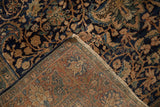 The hand-knotted construction and navy floral pile of a vintage Farahan Sarouk rug corner.