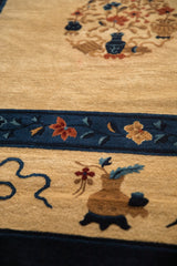 A detailed view of a scholar's vase and floral sprigs on an antique Peking carpet.