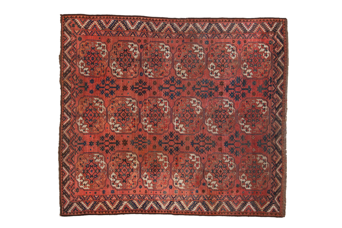 Antique Turkmen Beshir carpet with oversized floral guls in a geometric pattern of red, navy, and ivory.