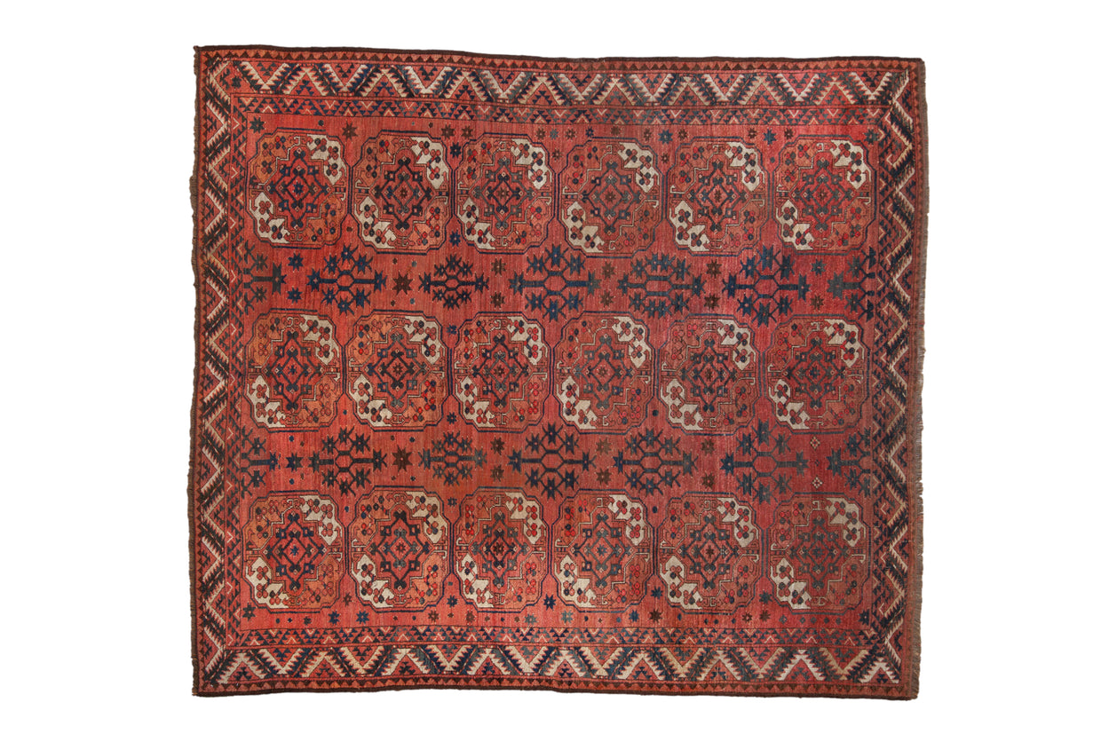 Antique Turkmen Beshir carpet with oversized floral guls in a geometric pattern of red, navy, and ivory.