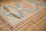Distressed antique Karabagh runner from an angle, highlighting its large serrated medallions and abrashed blue field.