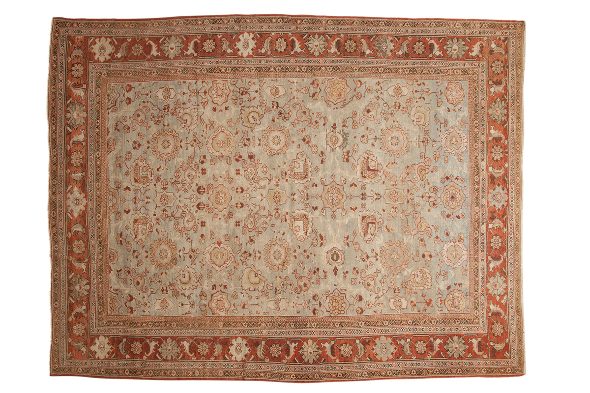 A distressed vintage Mahal carpet with an allover floral pattern in terracotta and beige over a soft, powder blue field.
