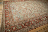 Angled view across the distressed pile of a vintage Mahal carpet showing its allover floral pattern.