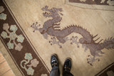 Five-toed dragon in mauve and brown on an antique Peking carpet with a dark chocolate floral border.