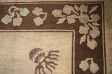 Detail of the antique Peking carpet's corner with blossomed flowers on a brown border.