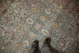 View from above showing the distressed texture and sprawling vine pattern of a vintage Tabriz carpet.