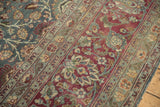 Decorative wear on a vintage Tabriz carpet showing detailed palmettes in teal and burgundy.