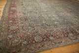 Ornate burgundy border and sprawling dusty teal field of a distressed vintage Persian Tabriz carpet.