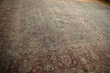 Angled view across the distressed pile of a vintage Tabriz carpet showing floral vines.