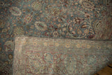 A folded corner of the distressed Tabriz carpet reveals its hand-knotted foundation and weave.