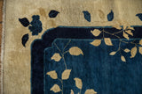 Intricate leaf vines on the scalloped navy and cobalt blue border of an antique Peking carpet.