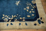 Scalloped corner contour of an antique Peking rug with beige vines against cobalt and navy blue.
