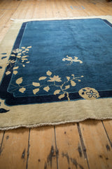 Angled view of the antique Peking carpet's scalloped corner and delicate ivory leaf patterns.