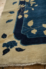Scalloped corner contour of an antique Peking rug with beige leaves on a navy blue ground.