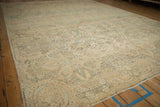 Low angle perspective across a vintage Kerman carpet highlighting its distressed, low-pile texture.