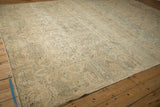 Angled perspective on a vintage Kerman rug showing its faded allover florals and distressed, low pile.