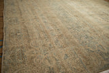 Angled view across the time-softened low pile of a distressed vintage Kerman carpet.