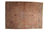 Vintage distressed Kerman carpet with a floral medallion and scrolling vines in soft sandalwood, blue, and red hues.