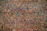 Corner detail of a vintage Persian Kerman showing intricate floral borders with sky blue and red vines.